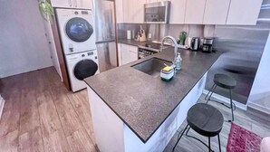 Uma cozinha moderna com máquina de lavar embutida, eletrodomésticos de aço inoxidável e um espaço de bar com banquetas.