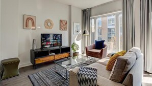 Uma sala de estar moderna com sofá, mesa de centro, TV e obras de arte na parede.