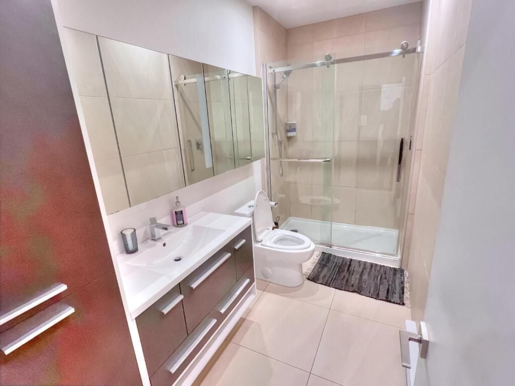 A modern bathroom with a glass shower enclosure, a white sink, and a large mirror.