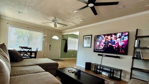 Een woonkamer met een bank, salontafel, televisie en plafondventilator.