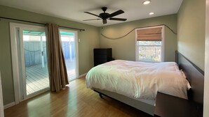 Een slaapkamer met een bed, plafondventilator en een raam met jaloezieën.