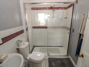 Casa de banho com sanita, bidé e cabine de duche envidraçada.