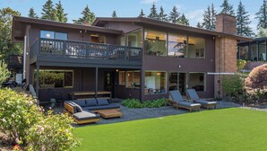 A modern two-story house with a balcony, outdoor seating, and a well-maintained lawn. - Seattle Mid-century Reteat (Burien)