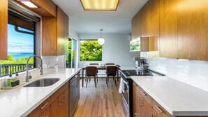 A modern kitchen with wooden cabinets, a white countertop, and a view of greenery outside. - Seattle Mid-century Reteat (Burien)