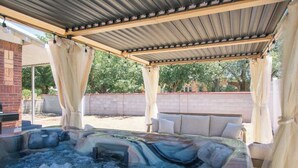 A hot tub under a covered patio with a brick wall and a white fence in the background. - French Tea House in Old Town+Private Hot Tub+Pet Friendly! (Albuquerque)