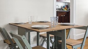 Ruokailutila, jossa on puinen pöytä ja tuolit, seinällä kehystetty taulu ja taustalla keittiö.