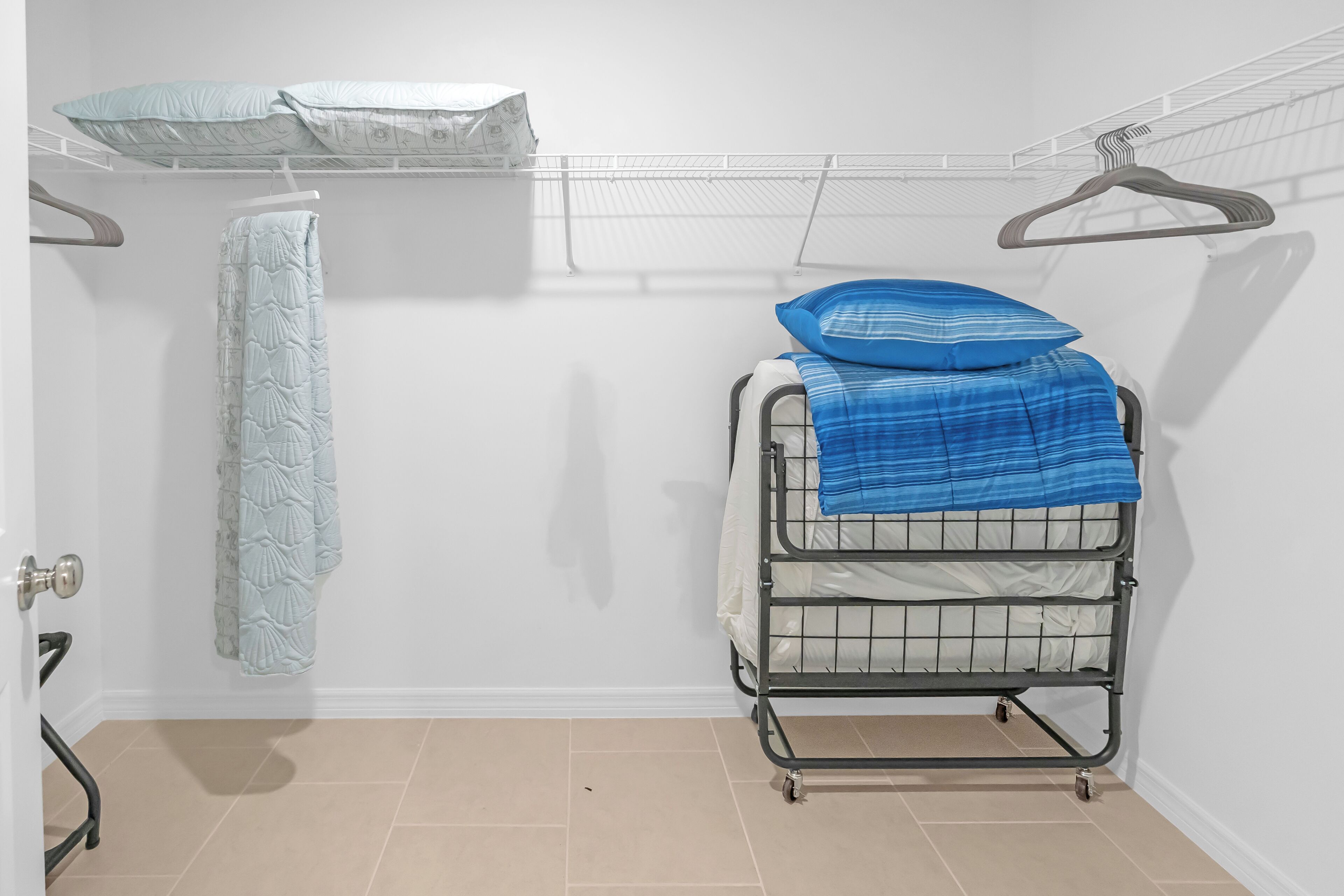 A small, clean room with a metal bunk bed, a hanging towel, and a white wall.