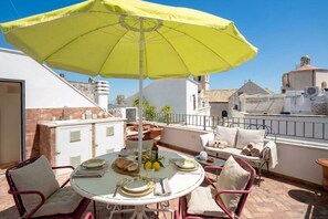 A rooftop terrace with a table set for dining, a yellow umbrella, and a view of the cityscape. - Dimora BoxFish | Elegance and Relaxation with a Private Terrace (Polignano a Mare)