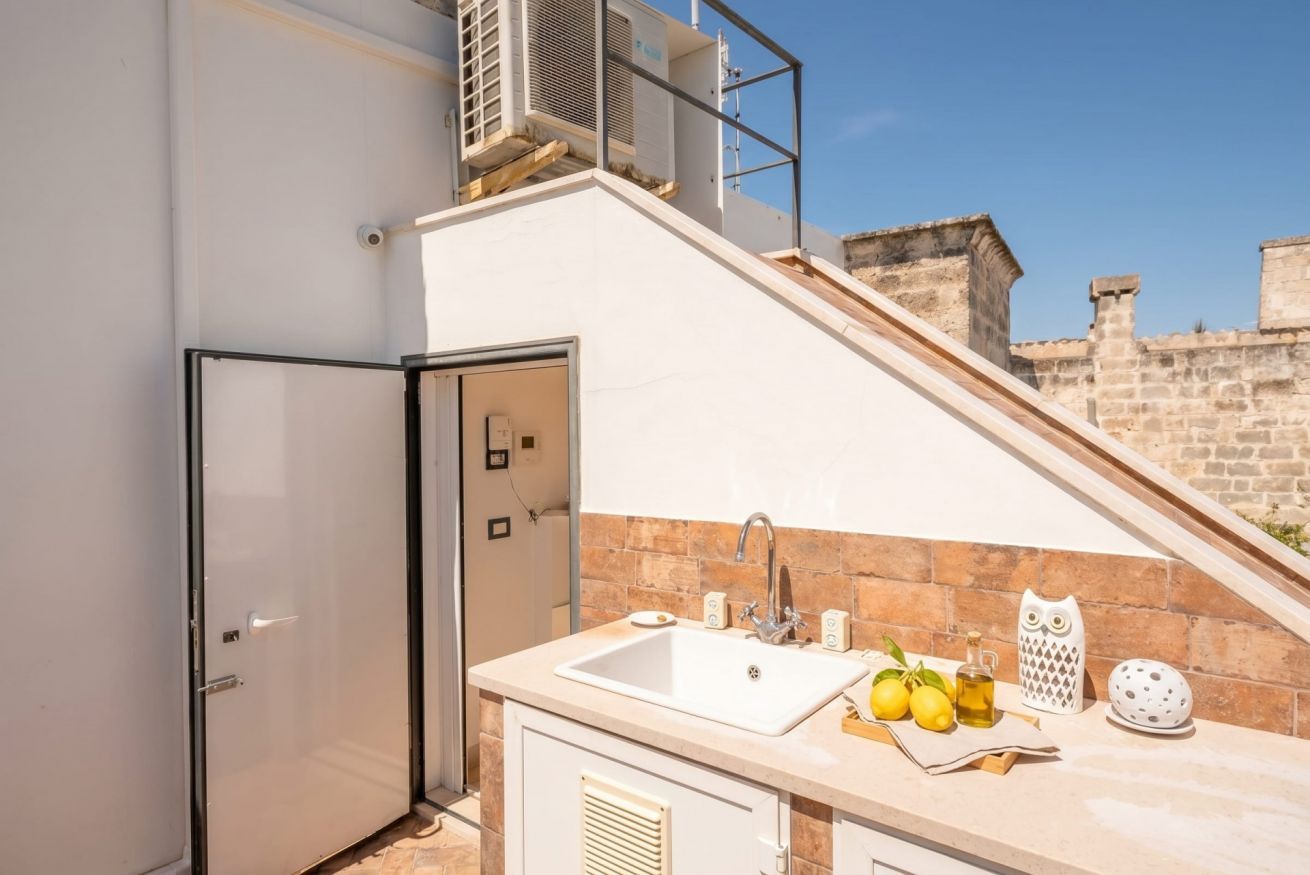 A compact kitchen with a sink, a refrigerator, and a window overlooking a stone wall.