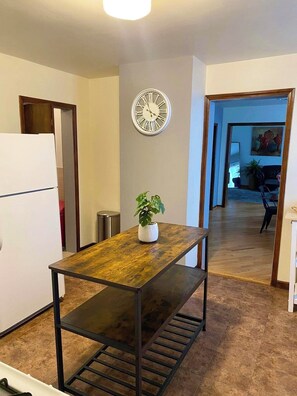 Une cuisine avec une table en bois, une horloge et une plante en pot.