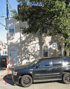 A black SUV parked in front of a two-story house with a visible door number.