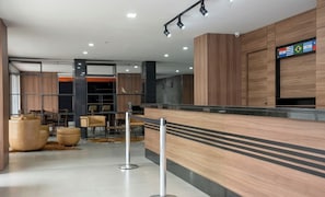 A modern lobby with a reception desk, seating area, and a wall displaying flags.