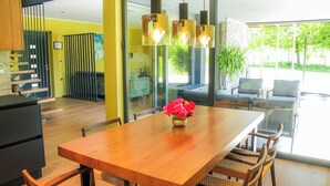 A modern kitchen with wooden cabinets, a dining table with chairs, and a vase of flowers.