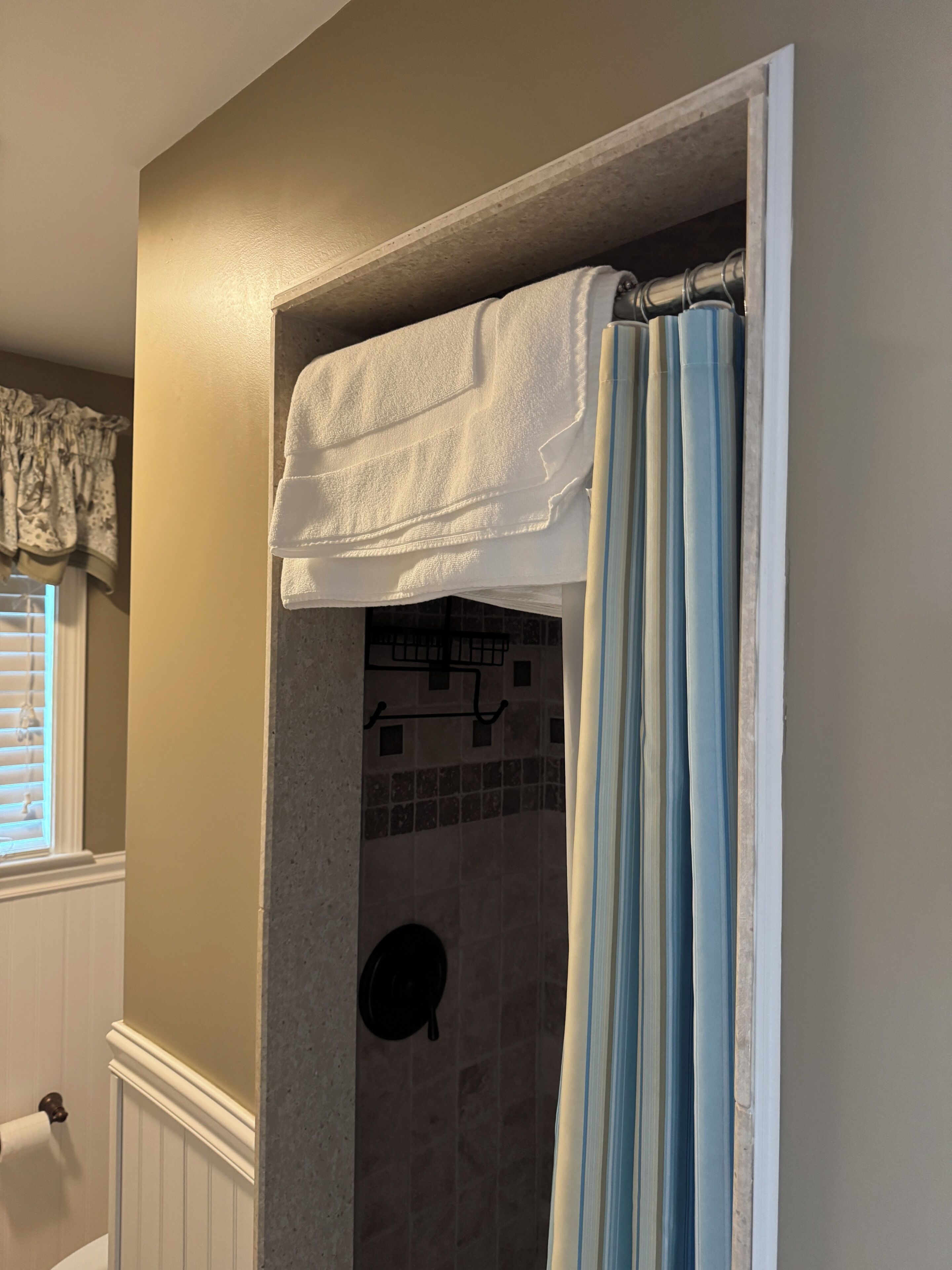Une salle de bain avec un rideau de douche, un porte-serviettes et une zone de douche carrelée.