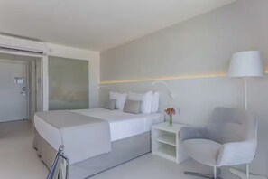 Una habitación de hotel moderna con cama, mesita de noche, silla y lámpara.