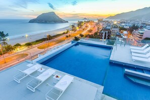 A rooftop pool with lounge chairs and a view of the beach and cityscape. - Elegant Beachfront Suite Perfect for a Romantic Getaway in Rio! (N/A)