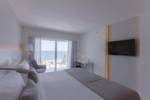 Ein Hotelzimmer mit Bett, Schreibtisch, Stuhl, Fernseher und Meerblick.