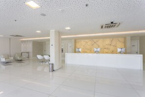 A modern hotel lobby with a reception desk, seating area, and a marble wall. - Spacious Ocean-Front Room Ideal for Relaxation | For Large Family or Groups! (N/A)