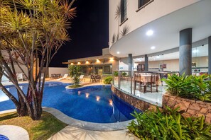 Una piscina con sillones de descanso y zona de comedor.