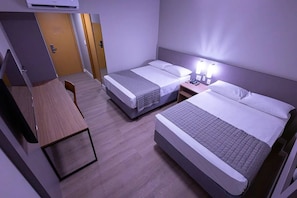 Une chambre d’hôtel avec deux lits, un bureau et une porte.