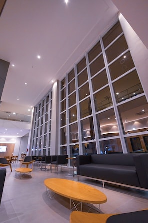 Eine großzügige Lobby mit großen Fenstern, moderner Sitzgelegenheiten und einer hohen Decke.