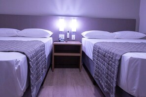 Ein Doppelzimmer mit zwei Betten, einem Nachttisch und Wandleuchten.