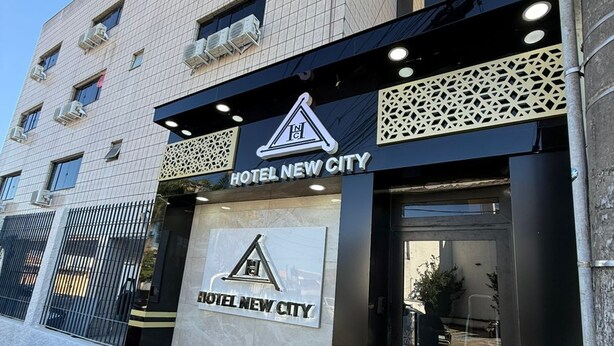 Ein moderner Hotel Eingang mit einem gut sichtbaren Schild, auf dem 'HOTEL NEW CITY' steht.