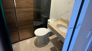 Ein modernes Badezimmer mit einer Duschkabine, einer Toilette und einem Waschbecken mit Marmorplatte.