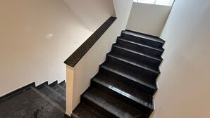 Eine Treppe mit schwarzen Stufen und einem weißen Geländer, die zu einer Empore führt.