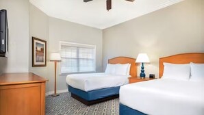 A hotel room with two beds, a ceiling fan, a window with blinds, a bedside table with a lamp, and a wooden dresser. - 7/19-7/24; 3BR/2BA WorldMark Kissimmee Suite. Family Fun, Free Shuttle to Disney (Kissimmee)