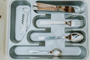 A tray with cutlery including a knife, fork, spoon, and a bottle opener.