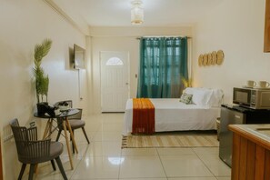 A hotel room with a bed, a desk with chairs, a microwave, and a television. - Tropical Nest Arima Near Airport Self Check-In (Arima)