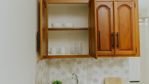 A kitchen with a wooden cabinet, a tiled backsplash, a sink, and a countertop.