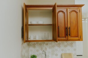 A kitchen with a wooden cabinet, a tiled backsplash, a sink, and a countertop.