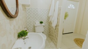 A bathroom with a toilet, sink, mirror, and towels.