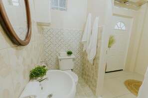 A bathroom with a toilet, sink, mirror, and towels. - Tropical Nest Arima Near Airport Self Check-In (Arima)