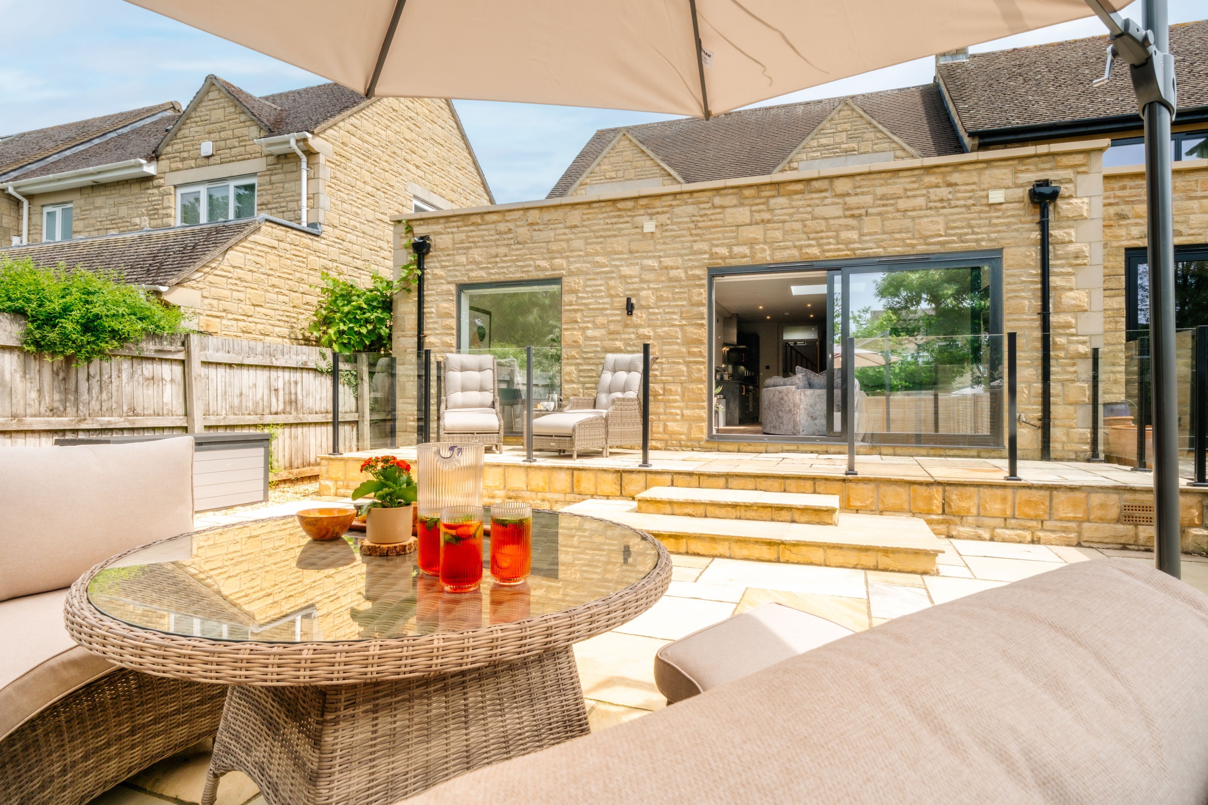 A rear raised terrace with garden furniture and a glazed balcony looks down to paved garden area