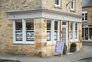 Ein Steinhaus mit einem Schild für 'Cotswolds Hideaways', das Landurlaube anbietet.