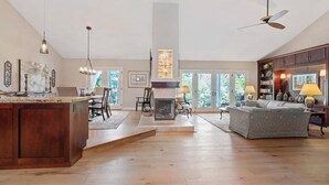 A spacious living area with a fireplace, dining area, and a large window. - Spacious 4BR Estate, Pickleball/Bball Court Surrounded by Trees on 0.74 acres (Poway)