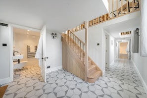 Ein modernes Badezimmer mit einer freistehenden Badewanne, einer Holztreppe und einem geometrisch gemusterten Boden.