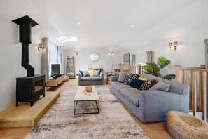 Ein Wohnzimmer mit Kamin, Sofas, einem Couchtisch und einer Treppe.