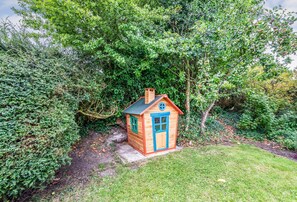 A small wooden cabin with a blue door and windows, surrounded by dense greenery. - Greygles (5) -Melcombe Bingham, Dorchester sleeps 5 guests  in 3 bedrooms (Melcombe Bingham)