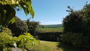A garden with a paved path, lush greenery, and a view of a distant field. - Greygles (Sleeps 5) -Melcombe Bingham, Dorchester sleeps 5 guests  in 3 bedrooms (Melcombe Bingham)