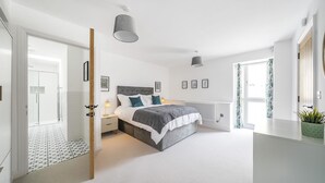Une chambre à coucher avec un lit, des tables de chevet, un radiateur et une fenêtre avec des rideaux.
