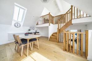 A spacious room with a wooden staircase, a dining area with a table and chairs, and a large window. - St Mary's Barn (Sleeps 4) - Stalbridge , Sherborne sleeps 4 guests  in 2 bedrooms (Stalbridge)