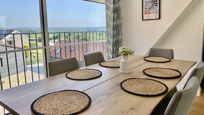 Un coin repas avec une grande table, quatre chaises et un vase rempli de fleurs.