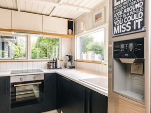 A modern kitchen with a built-in oven, a coffee maker, and a water dispenser. - 4 Star Holiday Home in Karrebaeksminde (Karrebæksminde)