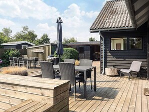 A wooden deck with outdoor furniture, including a table and chairs, and a covered area with an umbrella. - 4 Star Holiday Home in Karrebaeksminde (Karrebæksminde)
