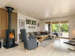 Un salon moderne avec un poêle à bois, un ensemble de canapés et un coin repas.