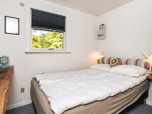Ein Schlafzimmer mit einem Bett, einem Fenster, einer Wandleuchte und einer Steckdose.